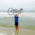 man holding bike over head in ocean