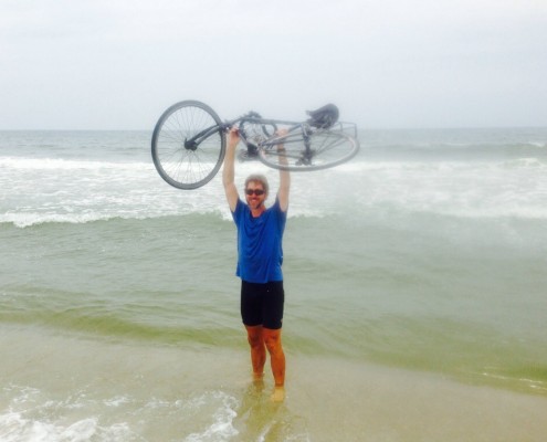 man holding bike over head in ocean